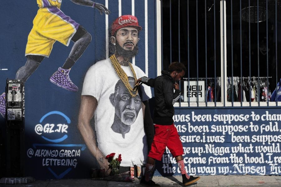 A+man+touches+a+mural+in+Los+Angeles+depicting+Hussle+on+April+2%2C+two+days+after+his+death.+Courtesy+of+Associated+Press.