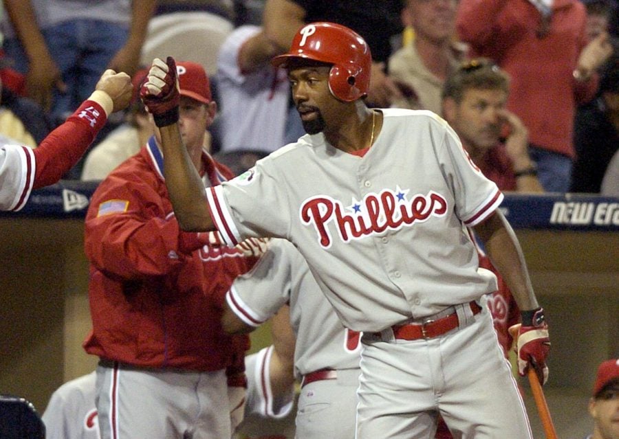 In this Aug. 5, 2004, file photo, Philadelphia Phillies Doug Glanville congratulates a teammate in the 10th inning against the San Diego Padres in San Diego. The Chicago Cubs say theyre investigating a fan using what appeared to be an offensive hand gesture associated with racism behind Glanville, now a television reporter, who was on the air for NBC Sports Chicago.