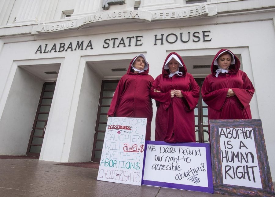 Three women protesting Alabamas new law banning nearly all abortions. The controversial law is the latest in a stream of bills designed to be challenged in court, with the potential to go to the Supreme Court.