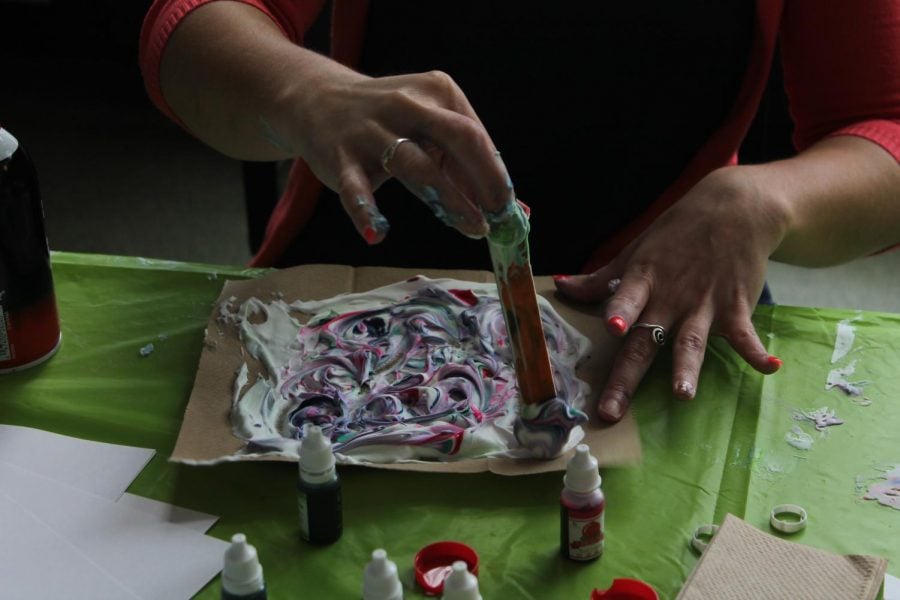 Stephanie Punda, the assistant director of fitness and wellness, uses a wooden stick to mix around a mixture of shaving cream and colored dyes to create marble art. After you put the dye on the shaving cream and mix it, you press a sheet of paper on top and wipe off the excess shaving cream to get you own artwork. 