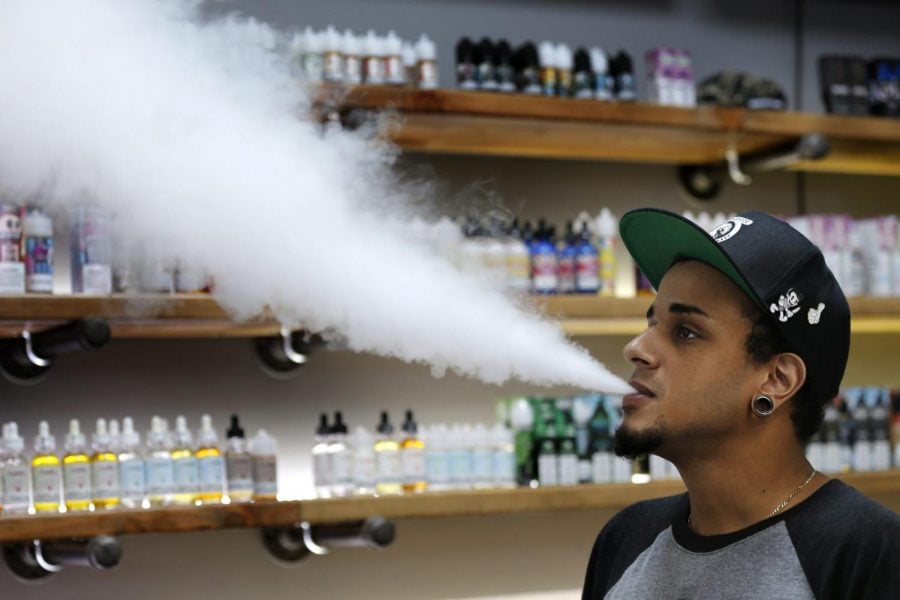 In this Tuesday, Sept. 3, 2019, photo, Andrew Teasley, a salesman at a Biddeford, Maine vape shop, exhales vapor while using an e-cigarette.