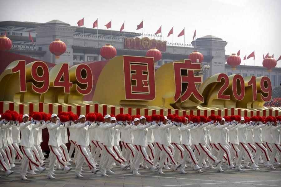 Participants wave flowers as they march next to a float commemorating the 70th anniversary of the founding of Communist China during a parade in Beijing, Tuesday, Oct. 1, 2019.