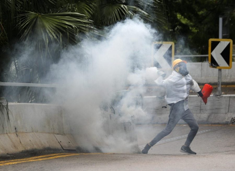 Protesters throw back tear gas at police in Hong Kong, Sunday, Oct. 6, 2019. Shouting Wearing mask is not a crime, tens of thousands of protesters braved the rain Sunday to march in central Hong Kong as a court rejected a second legal attempt to block a mask ban aimed at quashing violence during four months of pro-democracy rallies.
