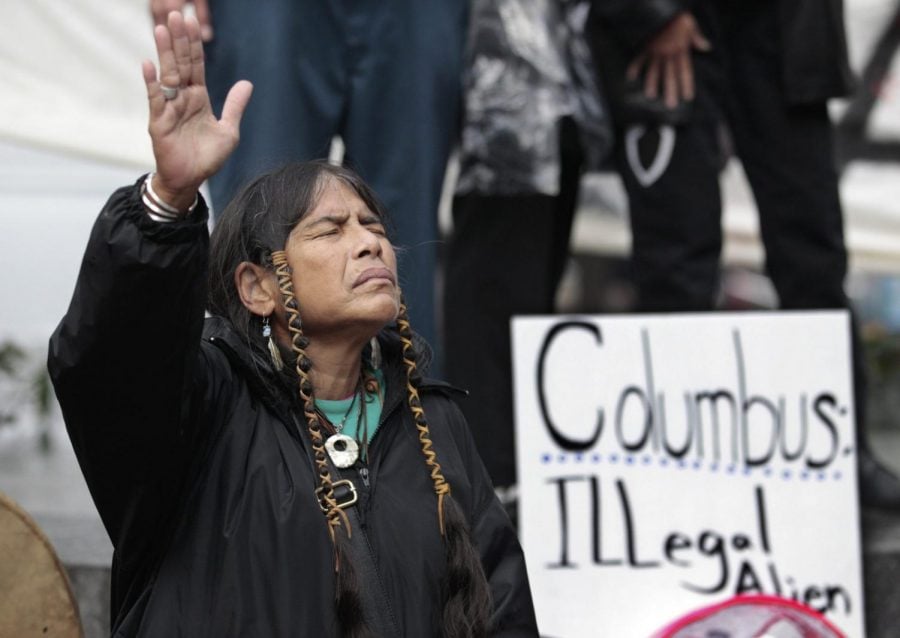 In this Monday, Oct. 10, 2011 file photo, Ferntree, of Duncan, British Columbia, a member of the Cowichan Tribes, holds her hand up as a prayer is given during a Native American protest against Columbus Day in Seattle. 