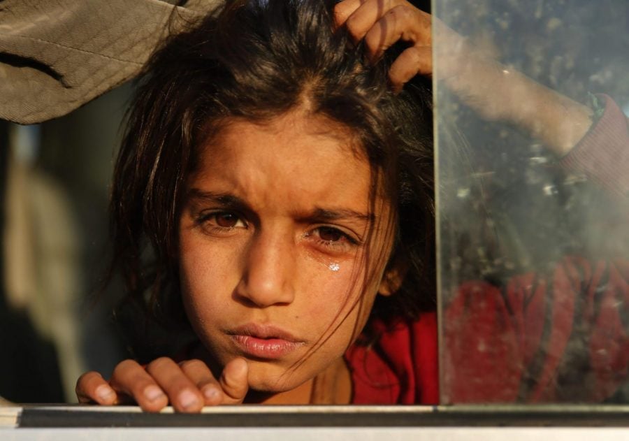 A Syrian girl who is newly displaced by the Turkish military operation in northeastern Syria, weeps as she sits in a bus upon her arrival at a camp in Mosul, Iraq, Wednesday, Oct. 16, 2019.