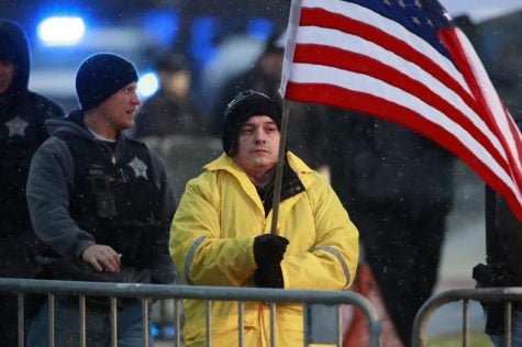 In this Nov. 25, 2018 file photo, State Rep. Jaime Andrade holds a flag outside the visitation for Chicago police Officer Samuel Jimenez at a funeral home in Des Plaines, Ill.A federal bribery charge against an Illinois legislator has led to questions about whether lawmakers be allowed to lobby other units of government. Illinois like most states allows legislators to lobby outside state government. Andrade said he registered as a Chicago lobbyist and started charging for his services when the state budget crisis from 2015 to 2017 forced lawmakers to go without paychecks.