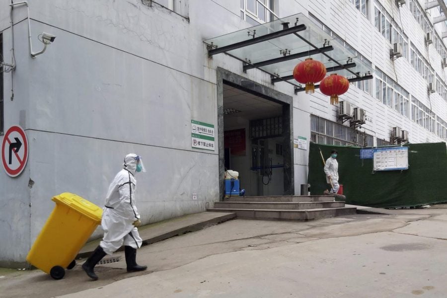 In this Thursday, Jan. 23, 2020, photo, a staff member wearing a hazardous materials suit hauls a bin at a hospital that reported a coronavirus death in Yichang in central Chinas Hubei Province. China is swiftly building a 1,000-bed hospital dedicated to patients infected with a new virus that has killed 26 people, sickened hundreds and prompted unprecedented lockdowns of cities during the countrys most important holiday.