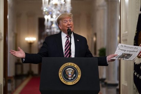 President Donald Trump holds up a newspaper that reads “Trump acquitted” during during an event celebrating his impeachment acquittal, in the East Room of the White House, Thursday, Feb. 6, 2020, in Washington.