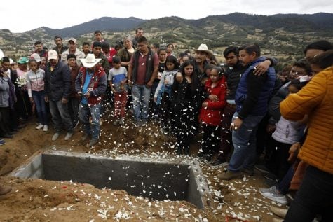 Los pétalos de las flores caen cuando familiares y amigos lloran alrededor de la tumba del activista comunitario Homero Gómez González en Ocampo, estado de Michoacán, México.