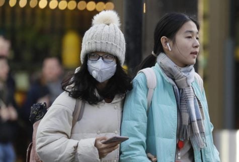 A woman wears a mask as she walks near Chinatown in London.