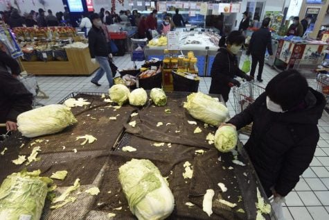 A woman, right, wears a face mask selects cabbage at a supermarket in Hangzhou in east China's Zhejiang province, Saturday, Feb. 8, 2020. China's communist leaders are striving to keep food flowing to crowded cities despite anti-disease controls, to quell fears of possible shortages and stave off price spikes from panic buying after most access to Wuhan was cut off Jan. 23. Food stocks in supermarkets ran low shortly after Beijing imposed travel curbs and extended the Lunar New Year holiday to keep factories, offices and other businesses closed and the public at home, attempting to prevent the virus from spreading.