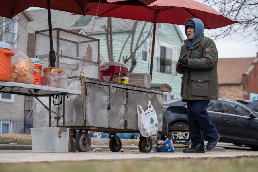 Don Arnulfo Tovar Ruiz camina frente a su carrito de comida en el barrio de Pilsen. Tovar Ruiz gana entre 10-20 dólares por día.