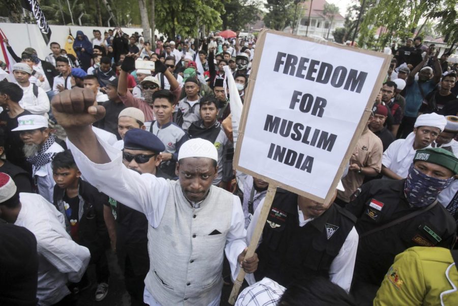 A Muslim man holds up a poster during a rally outside the Indian Consulate General in Medan, North Sumatra, Indonesian Monday, March 2, 2020.