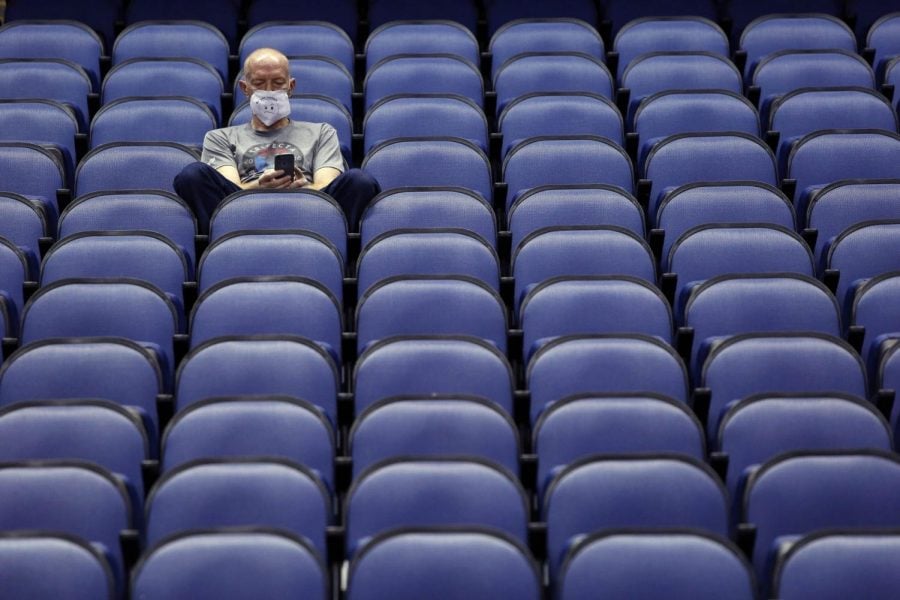 Mike Lemcke, from Richmond, Va., sits in an empty Greensboro Coliseum after the NCAA college basketball games were canceled at the Atlantic Coast Conference tournament in Greensboro, N.C., Thursday, March 12, 2020. 