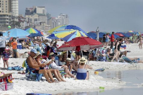 People gather on the shoreline in Destin, Fla., Wednesday, March 18, 2020.