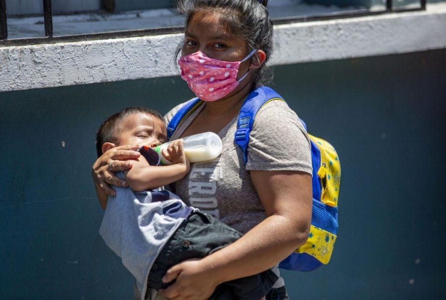 La viuda de un conductor de autobús que fue víctima de violencia hace fila con su hijo, mientras espera comida del Ministerio de Desarrollo Social de la Ciudad de Guatemala. 