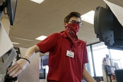 Un cajero trabaja en una caja registradora mientras se cubre la cara con un pañuelo en el supermercado de Jewel Osco en Mount Prospect, Illinois.