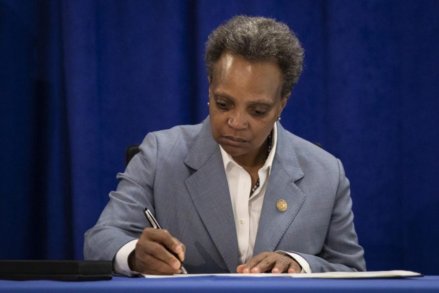 Chicago Mayor Lori Lightfoot signs an executive order to ensure coronavirus-related benefits offered by the city of Chicago are available to immigrants and refugees, Tuesday morning, April 7, 2020.