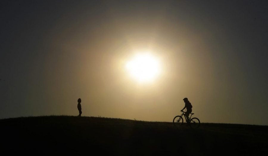 A cyclist tops a hill in a park at sunset in San Antonio, Monday, April 13, 2020. San Antonio is under stay-at-home orders due to the coronavirus pandemic, but parks have remained open for exercise and physical activity as long as social distancing is observed.