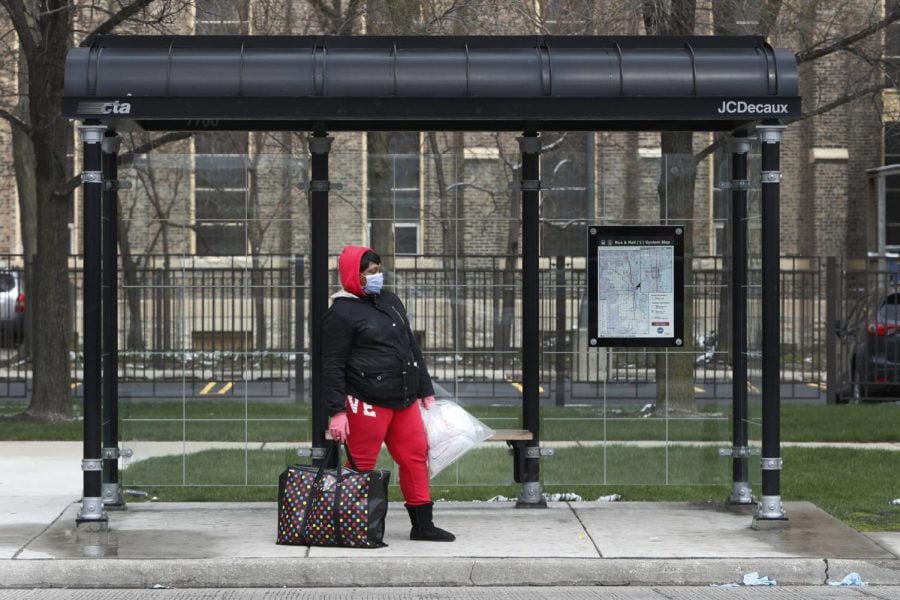 A woman waits at a Chicago Transit Authority bus shelter during the coronavirus pandemic on the citys West Side Wednesday, April 15, 2020.