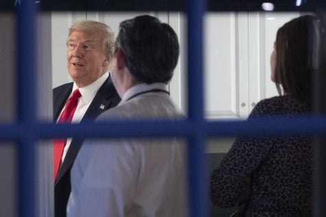 As seen through a window, President Donald Trump watches newscasts in an area behind the James Brady Press Briefing Room with Steven Groves, center, White House deputy press secretary, and press assistant Margo Martin, after speaking about the coronavirus at the White House, Friday, April 17, 2020, in Washington. Public health experts are becoming concerned that people will use their partisan identification to decide which officials to believe whenever parts of the country start edging back to a new normal.
