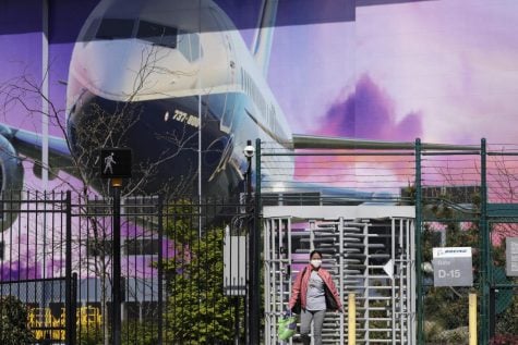A masked worker departs a gate at a Boeing production plant Monday, April 20, 2020, in Renton, Wash. Boeing this week is restarting production of commercial airplanes in the Seattle area, putting about 27,000 people back to work after operations were halted because of the coronavirus.