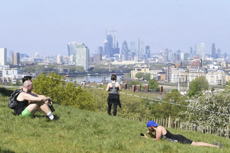 People sit on the grass in Greenwich Park, London as the UK continues in lockdown to help curb the spread of the coronavirus, Sunday April 26, 2020. The highly contagious COVID-19 coronavirus has impacted on nations around the globe, many imposing self isolation and exercising social distancing when people move from their homes.