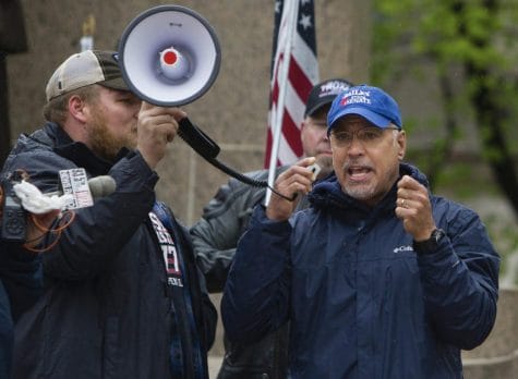 In this April 25, 2020 file photo, Illinois State Rep. Darren Bailey, R-Xenia, right, speaks at a protest against Gov. J.B. Pritzker's stay-at-home order in front of the Capitol building in Springfield, Ill., during the coronavirus outbreak. A judge in southern Illinois ruled Monday, April 27, 2020, that Pritzker's stay-at-home order to stem the spread of the coronavirus exceeds his emergency authority and violates individual civil rights.