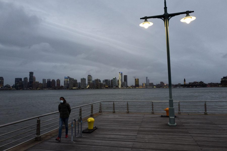 A man wears a face mask as he walks on Pier 45 in Hudson River Park, Thursday night, April 30, 2020, in New York.