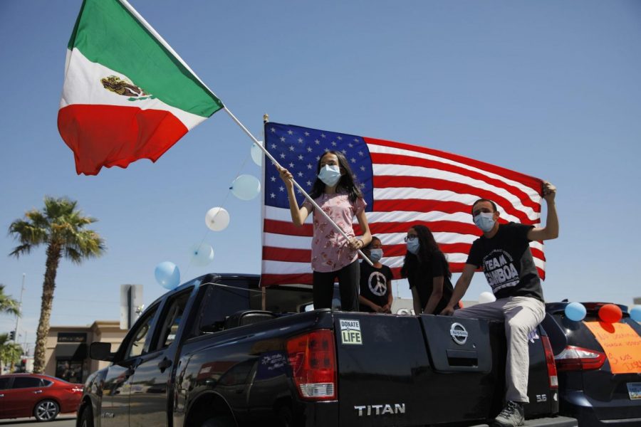Melany Gamboa, de doce años, sostiene una bandera mexicana mientras su familia sostiene una bandera estadounidense durante un mitin. 