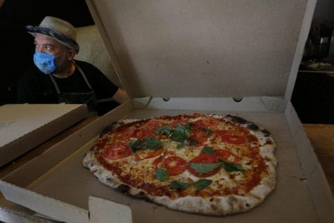 Wearing a mask against the spread of the new coronavirus, Eduardo Loyola boxes a pizza for delivery at the Zaza Pizzeria in Mexico City, Sunday, May 3, 2020.