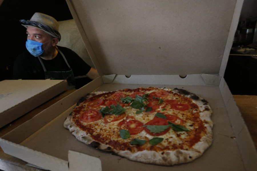 Wearing a mask against the spread of the new coronavirus, Eduardo Loyola boxes a pizza for delivery at the Zaza Pizzeria in Mexico City, Sunday, May 3, 2020.