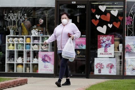 A woman wears mask as she leaves a store during the coronavirus pandemic in Deerfield, Ill., Tuesday, May 5, 2020. New Illinois rules about wearing a face mask over age 2 start Friday, May 1, when they can't maintain a 6 foot social distance in public.