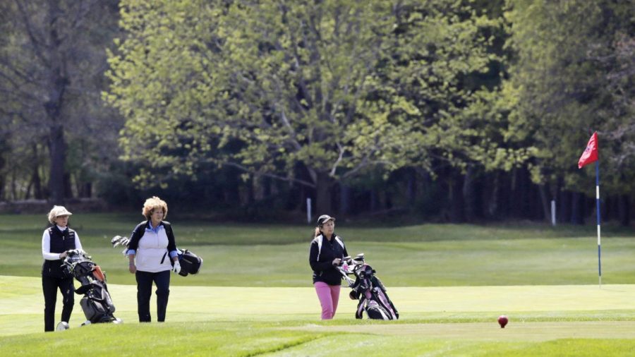 A group of golfers walks with their clubs off a green at the Weston Golf Club, in Weston, Mass., Thursday, May 7, 2020. Golf courses across Massachusetts were allowed to reopen on Thursday, with new social distancing and other health requirements, after they were closed due to the COVID-19 virus outbreak.