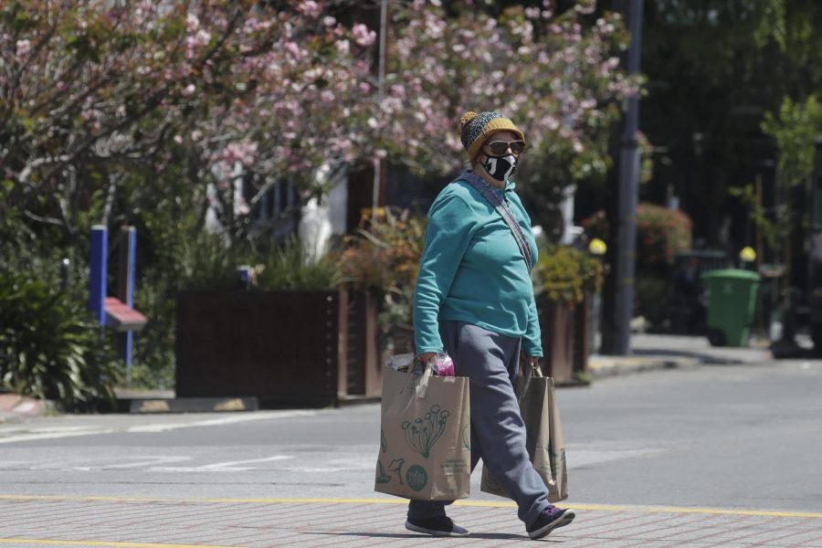 Virginia Nielsen wears a mask while carrying shopping bags during the coronavirus outbreak in San Francisco, Thursday, May 7, 2020.