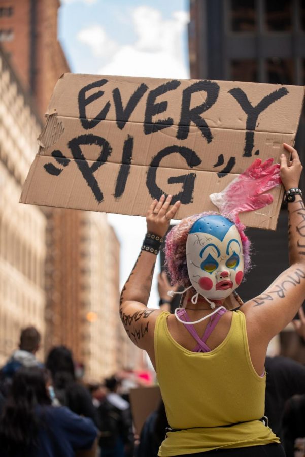 A masked protester raises their sign.