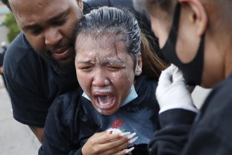 A woman is helped after being hit with pepper spray after curfew on Sunday, May 31, 2020 in Minneapolis. Protests continued following the death of George Floyd, who died after being restrained by Minneapolis police officers on Memorial Day.
