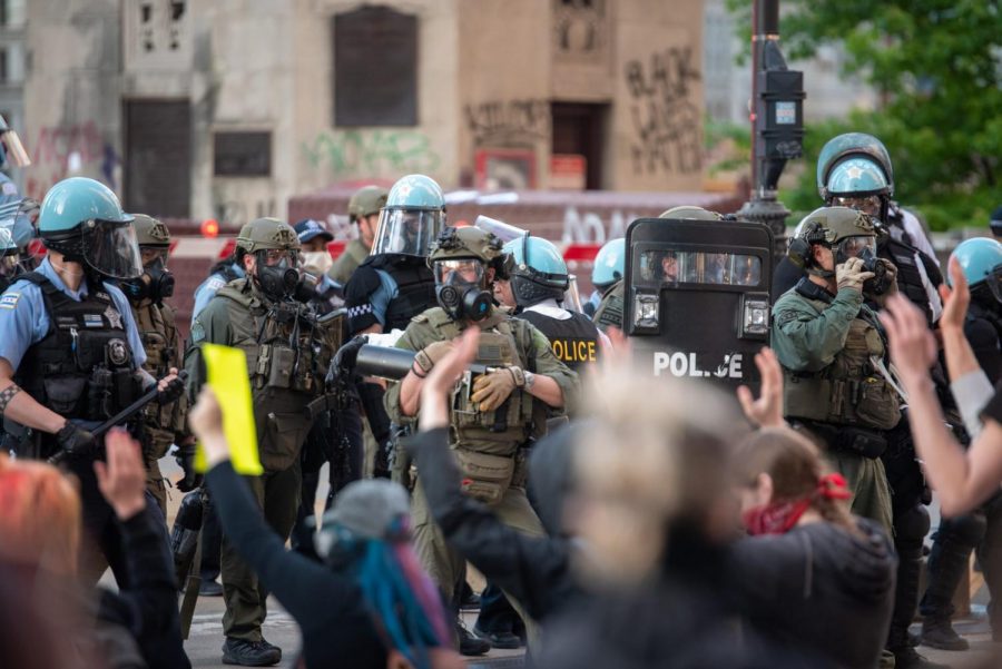 Oficiales con porras y escudos se enfrentan a los manifestantes.
Officers with batons and shields face protesters.

