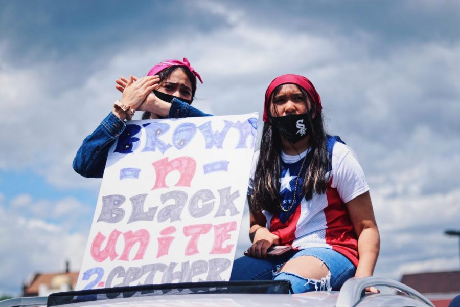 Two women hold up a protest sign in solidarity with the black community. 