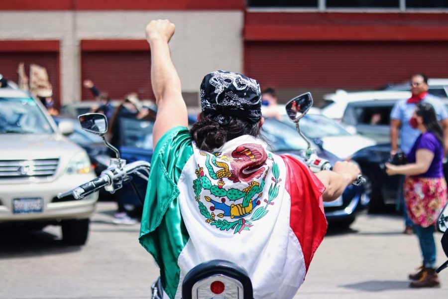 Un hombre lleva una bandera mexicana en una motocicleta detrás de la caravana de La Villita.
A man wears a Mexican flag on a motorcycle behind the Little Village caravan. 