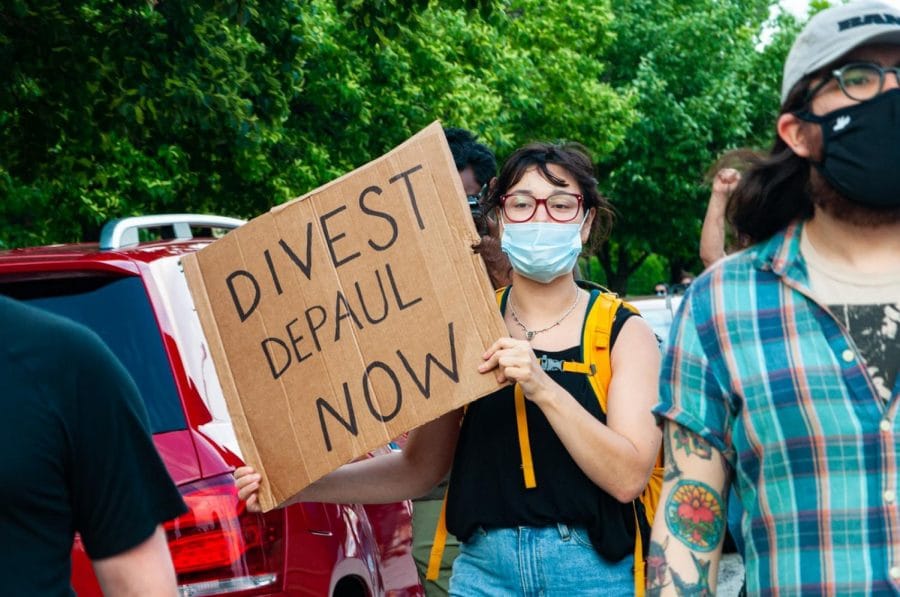 A DePaul student holds a sign at a June protest, calling for DePaul to divest from the Fraternal Order of Police. 