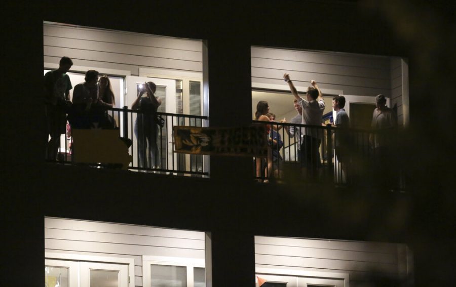 Partiers congregate on the balcony of a downtown apartment on Tuesday, Sept. 1, 2020, in Columbia, Mo., near the University of Missouri campus. Many colleges quickly scrapped in-person learning in favor of online after cases began to spike, bars have been shut down in college towns, and students, fraternities and sororities have been repeatedly disciplined for parties and large gatherings. (Dan Shular/Missourian via AP)