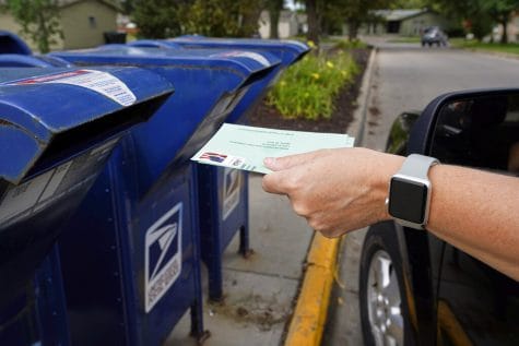 FILE - In this Tuesday, Aug. 18, 2020, file photo, a person drops applications for mail-in-ballots into a mail box in Omaha, Neb. Mail voting is starting in the presidential election as North Carolina is sending out its first batch of ballots. The battleground state on Friday begins to send out about 600,000 ballots to voters who've requested them. Those voters are overwhelmingly Democrats and independents, reflecting a partisan split in voting methods that's developed since President Trump started attacking mail voting in March. (AP Photo/Nati Harnik, File)