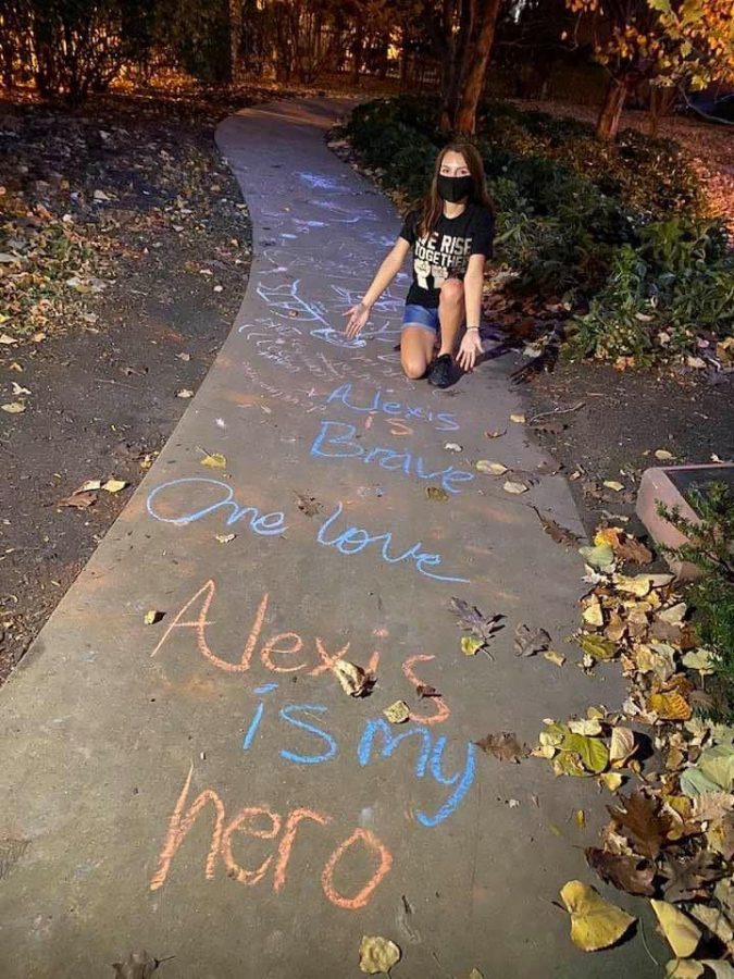 Alex Hadac, 19, kneels behind chalk art. Residents of the South Loop came together to embrace chalk art after Hadac was verbally and physically assaulted.