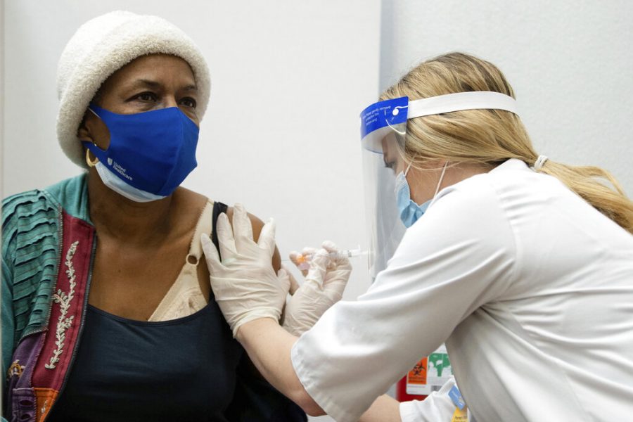 Megan Dewitt inoculates Alice Collins with the Moderna COVID-19 vaccine at a Walmart in the Austin neighborhood, of Chicago, Tuesday, Feb. 2, 2021.  (Pat Nabong/Chicago Sun-Times via AP)
