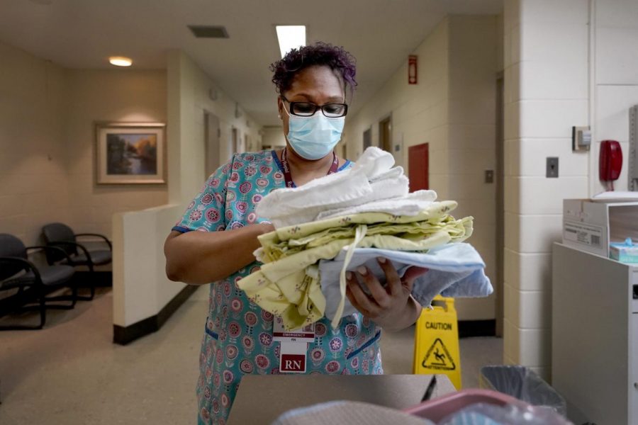 Roseland Community Hospital RN Rhonda Jones, prepares bed linens, towels and a hospital gown Friday, Jan. 29, 2021, for a new patient at the South Side of Chicago hospital. Jones has treated many patients with severe COVID-19, a relative died from it, and her mother and a nephew were infected and recovered, but she is still holding out getting the vaccine. (AP Photo/Charles Rex Arbogast)