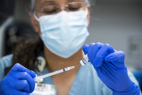 FILE - In this Thursday, Feb. 11, 2021 file photo, pharmacy technician Sochi Evans fills a syringe with a Pfizer-BioNTech COVID-19 vaccine at Texas Southern University in Houston. Coronavirus cases are continuing to decline in the U.S. after a winter surge. Researchers at Johns Hopkins University say the seven-day average of new coronavirus cases in the country dropped below 100,000 on Friday, Feb. 12 for the first time since November 4. (Brett Coomer/Houston Chronicle via AP, File)