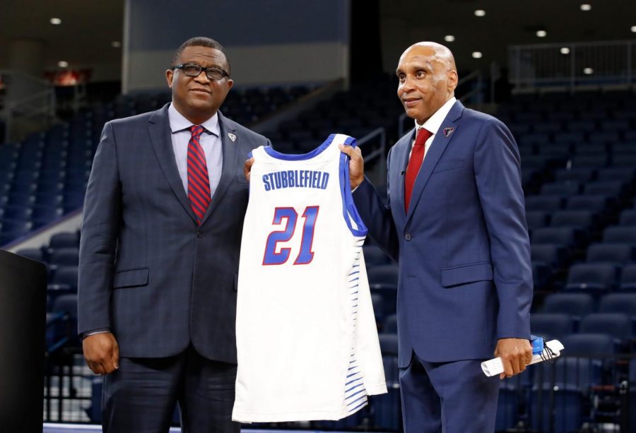 DePaul athletic director DeWayne Peevy hands Tony Stubblefield a No. 21 Blue Demon jersey at a Stubblefield's introduction as head coach in 2021.