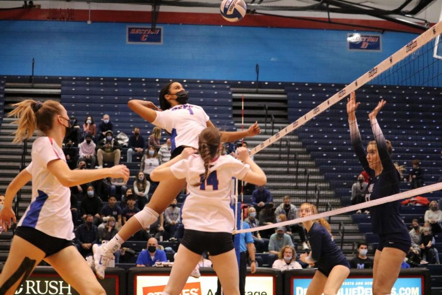 DePaul middle blocker Donna Brown jumping for a hit from setter Molly Murphy while right side hitter Emma Price looks on.