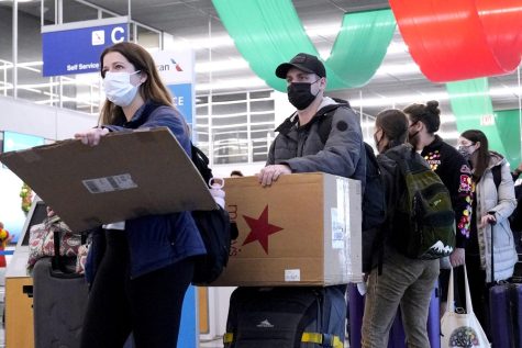 Travelers line up wearing protective masks indoors at OHare International Airport in Chicago, Tuesday, Dec. 28, 2021. Illinois Gov. J.B. Pritzker said Wednesday, Feb. 9, 2022, that at the end of the month he will lift the requirement for face coverings to be worn in most indoor spaces to slow the spread of COVID-19, but the mandate will stay in place for K-12 schools where students, teachers and staff are clustered together. (AP Photo/Nam Y. Huh, File)